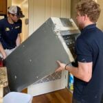 Two men moving a heavy appliance